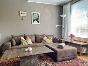 A living room with a brown sectional sofa, a marble coffee table, a patterned rug, and a window with blinds. - Bergulme Vacation Rental with a View of the Tyrolean Mountains (Mutters)
