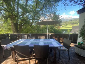 An outdoor patio with a table and chairs, a large umbrella, and a view of mountains. - Bergulme Vacation Rental with a View of the Tyrolean Mountains (Mutters)