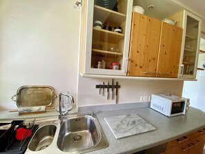 A kitchen with a stainless steel sink, a microwave, wooden cabinets, and a marble countertop. - Bergulme Vacation Rental with a View of the Tyrolean Mountains (Mutters)