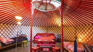 Une yourte traditionnelle avec un lit au centre, deux petits tabourets et un auvent au-dessus.