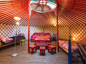 A traditional yurt with a central bed, two small stools, and a canopy overhead. - Authentic yurt - 3 guests (Plessix-Balisson (22))
