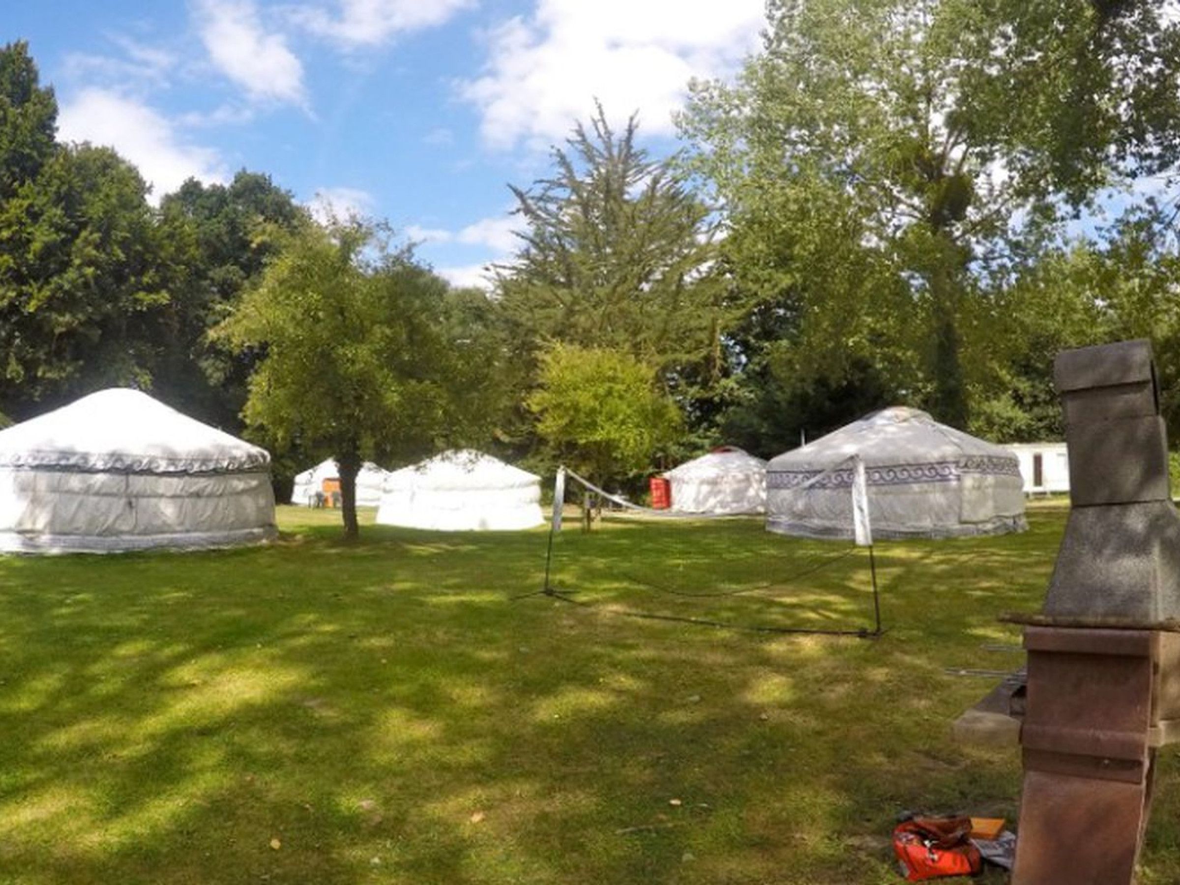 Yurts in a grassy area with trees in the background.