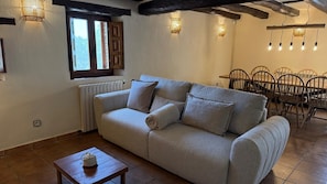 Un saló acollidor amb un sofà, una taula petita i una zona menjador amb cadires.