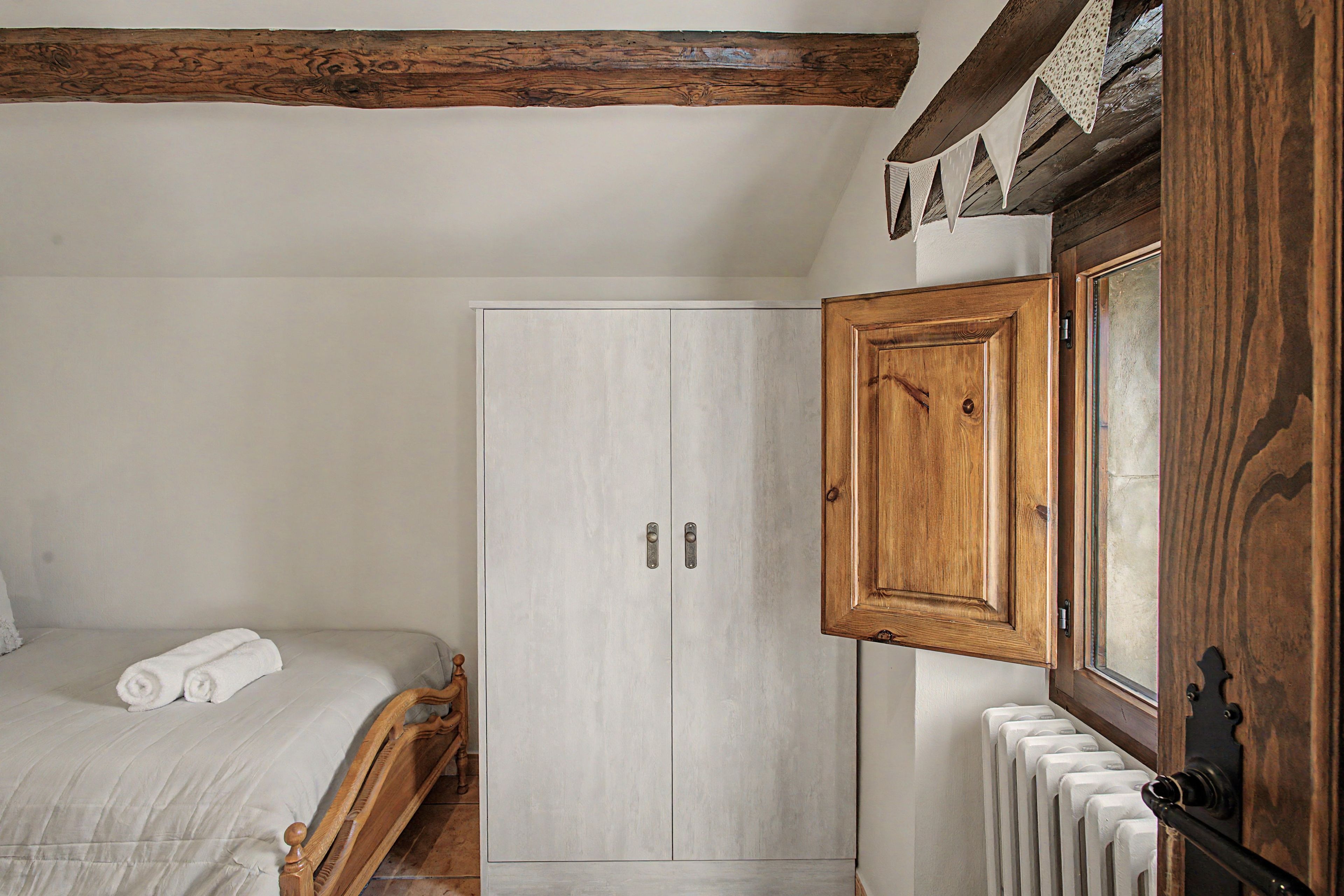 Un dormitorio con cama, armario y radiador.