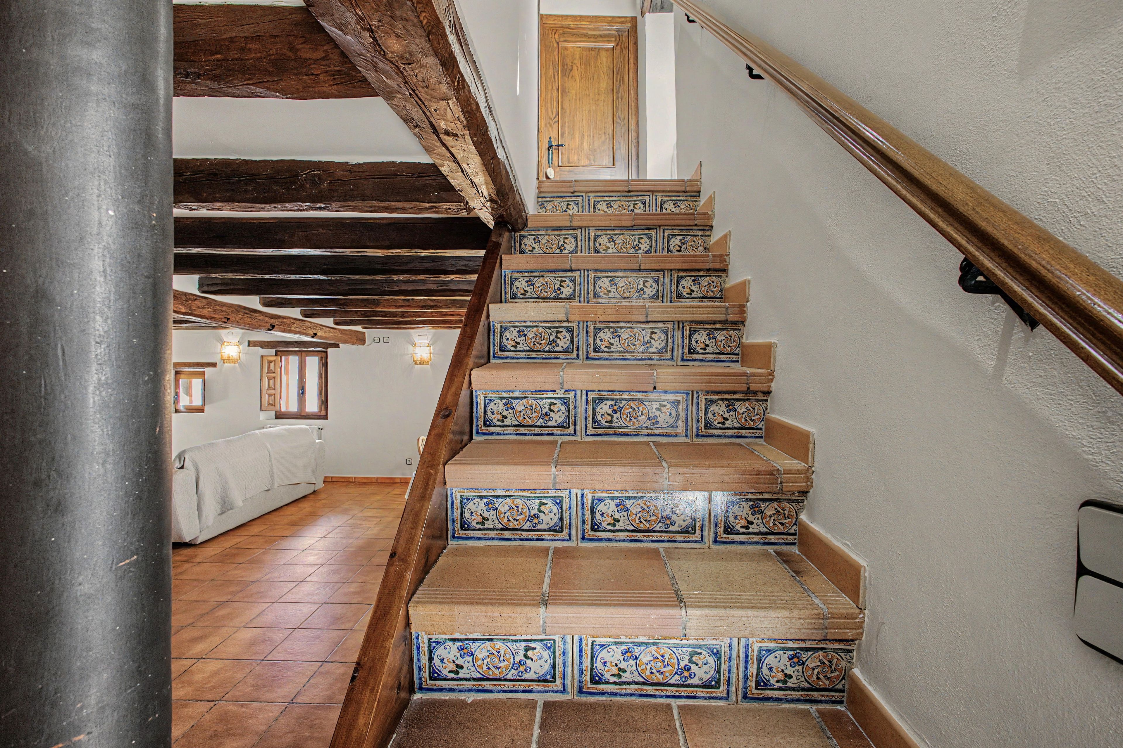 Uma escadaria com azulejos estampados e vigas de madeira.