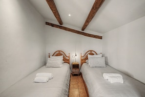 A bedroom with two single beds, wooden headboards, a nightstand, and a bedside lamp. - Country House 'El Casó Rural' with Private Pool in the Heart of Berguedà (Sorba - Montmajor)
