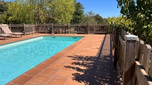 Una piscina rectangular amb aigua cristal·lina blava, envoltada per un terra de fusta i una tanca de fusta.