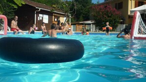 Ein Swimmingpool mit klarem Wasser, ein schwarzes schwimmendes Objekt und Personen im Hintergrund.