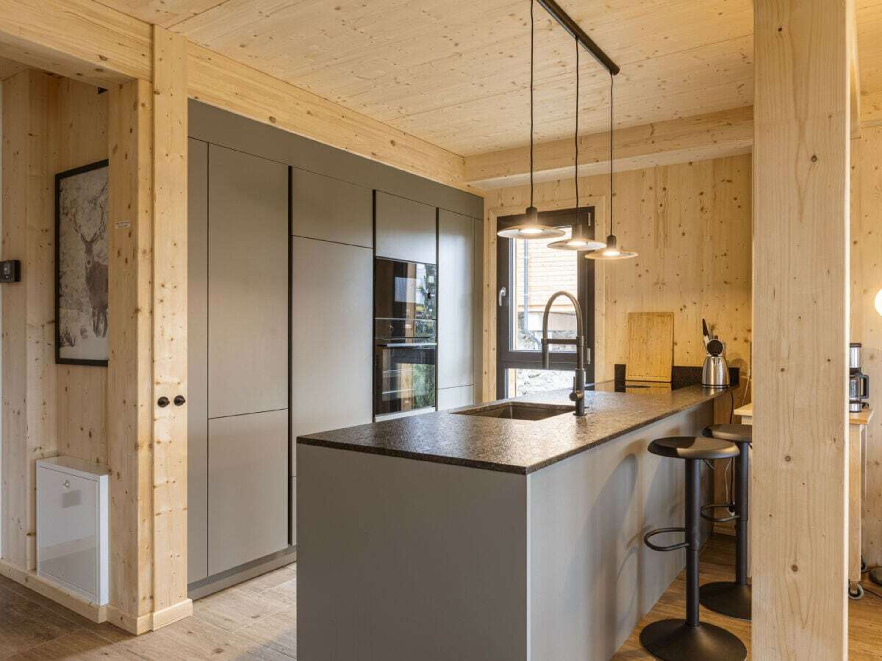 Een moderne keuken met een centraal eiland, hangende verlichting en houten lambrisering.