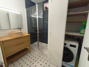 A bathroom with a glass shower enclosure, a wooden vanity with a sink, and a washing machine. - Apartment with sea view - 4 guests (Argelès-sur-Mer)