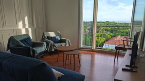 A living room with a large window, a sofa, two armchairs, a small table, and a TV. - Apartment with sea view - 4 guests (Argelès-sur-Mer)