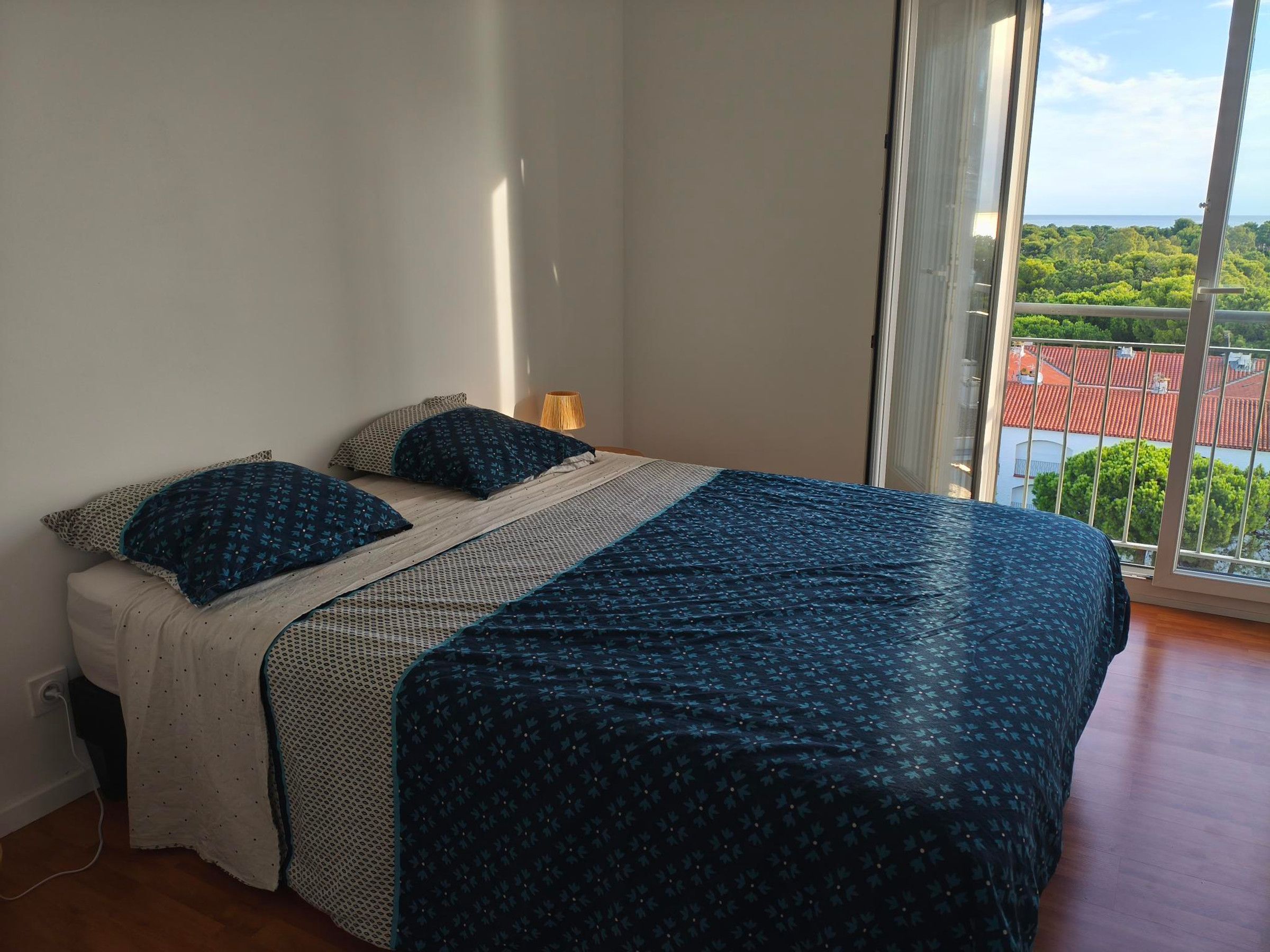 Makuuhuoneessa on sänky, lamppu ja suuri ikkuna, josta avautuu näkymä punakattoiseen rakennukseen.