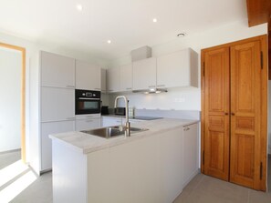 A modern kitchen with white cabinetry, a stainless steel sink, and a built-in oven.
