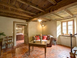 A rustic interior with a wooden ceiling, a sofa with cushions, a table with a vase, and a window with plants. - Spacious lodging with pool - 18 guests (Saint-Just-la-Pendue)