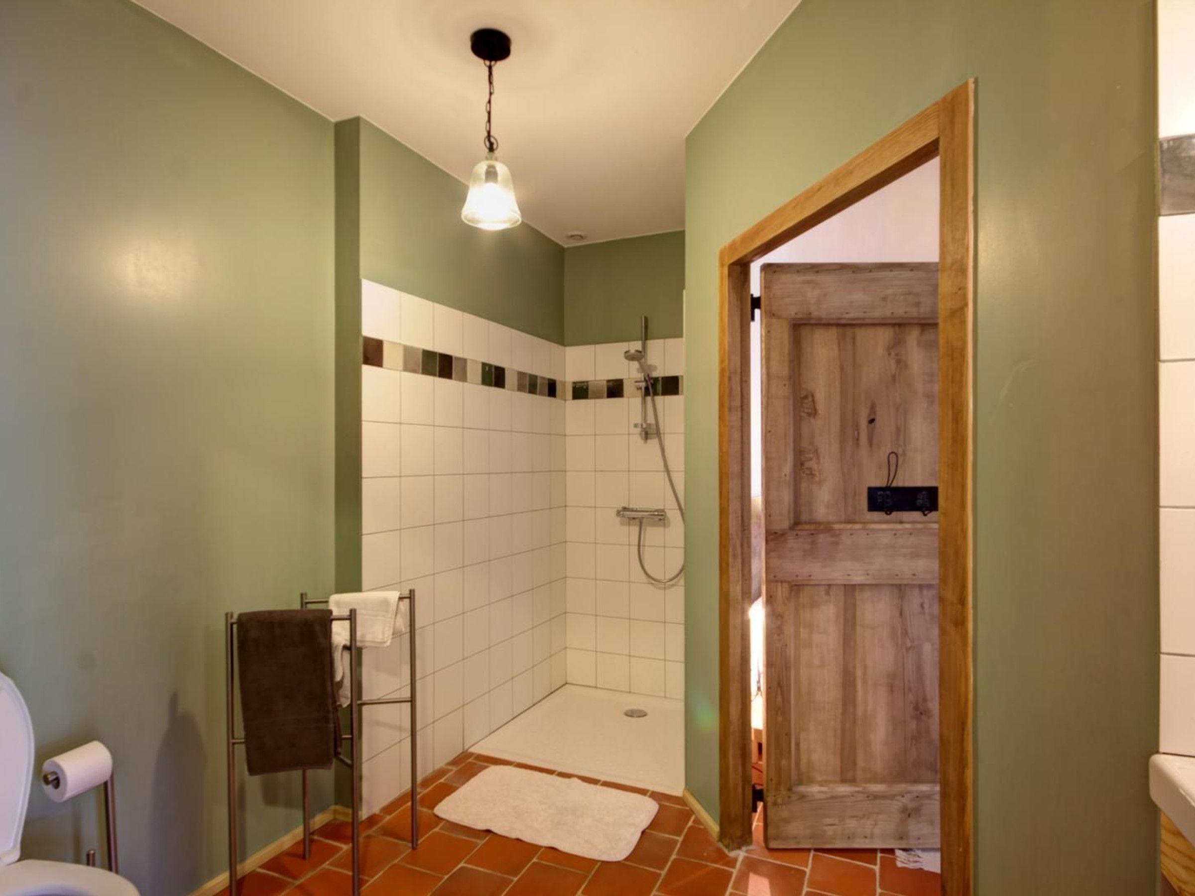 Een badkamer met een douche, toilet en een handdoekrek.