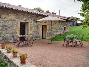 A stone building with a tiled roof, outdoor seating with metal chairs and tables, and potted plants. - Spacious lodging with pool - 18 guests (Saint-Just-la-Pendue)