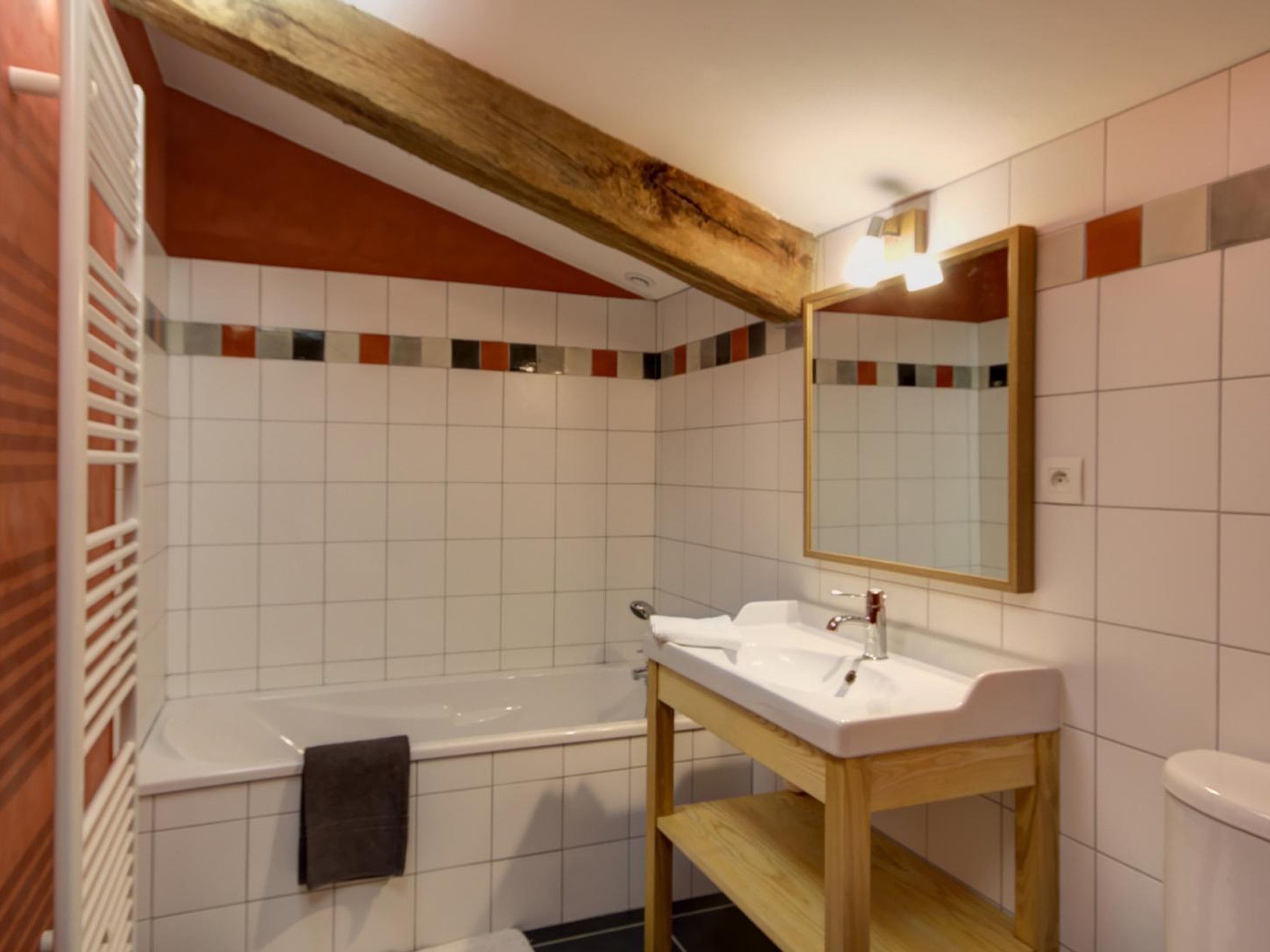 A bathroom with a wooden vanity, a white sink, a mirror, and a bathtub.