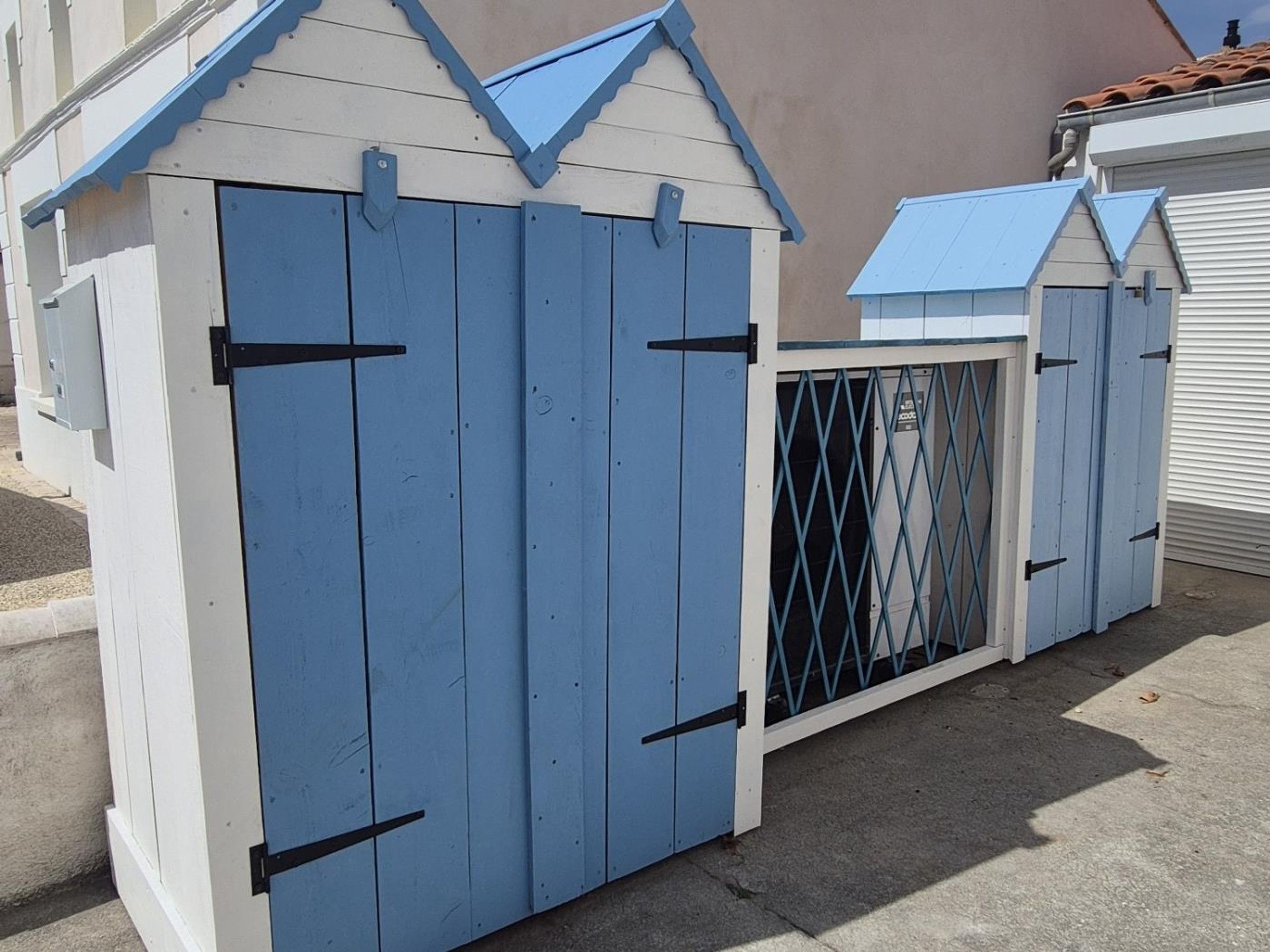 Une structure bleue et blanche avec un toit triangulaire, qui pourrait être un abri de jardin ou un petit bâtiment.