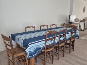 Una mesa de comedor con mantel a rayas, rodeada de sillas de madera con asientos de mimbre.
