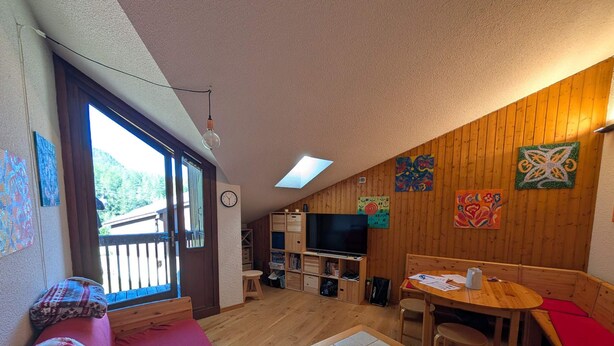 Une pièce chaleureuse avec un plancher en bois, une table à manger, un canapé et un téléviseur.