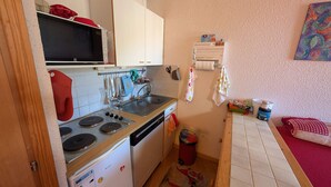 Une cuisine compacte équipée d’un four à micro-ondes, d’une cuisinière, d’un évier et d’un réfrigérateur.