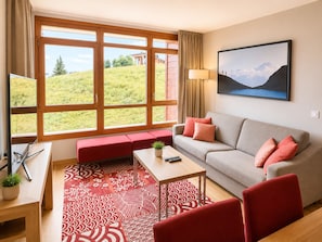 Ein modernes Wohnzimmer mit einer Couch, einer roten Bank, einem Couchtisch und einem großen Fenster mit Blick auf eine grüne Landschaft.