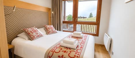 Ein Hotelzimmer mit einem Bett, einem Vorhangfenster, einem Holz-Kopfteil und einer Heizung.