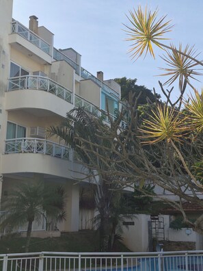 A multi-story building with balconies, a swimming pool, and tropical vegetation. - Itaipu loft penthouse (Niterói)