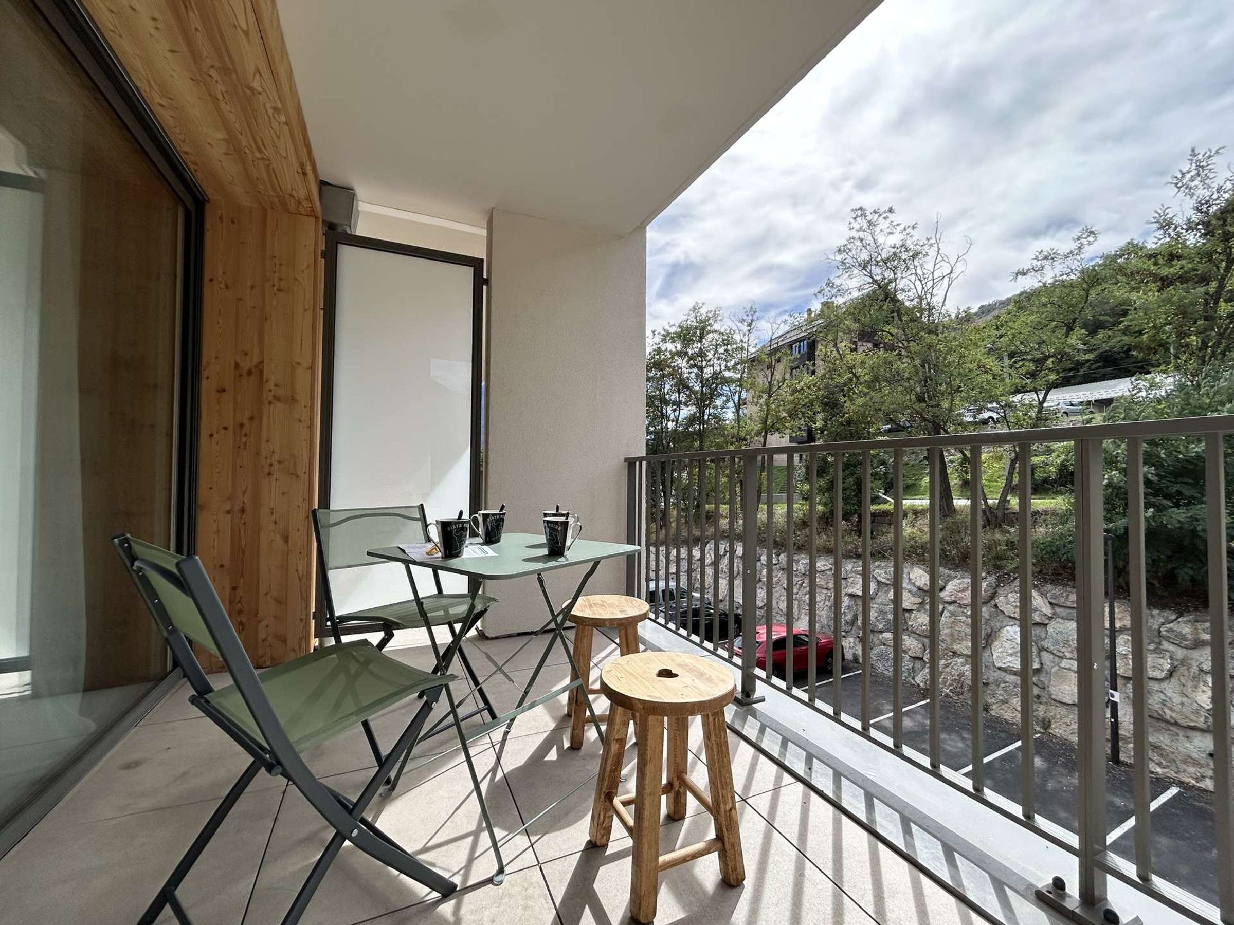 Een balkon met een tafel en stoelen, uitzicht op het omliggende landschap en een hekwerk.