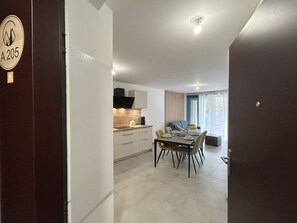 A modern kitchen with a dining area, a sofa, and a view of the outdoors. - New and spacious apartment - 4 guests (Briançon)