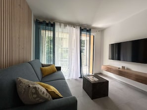 A modern living room with a grey sofa, a coffee table, and a flat-screen TV mounted on the wall. - New and spacious apartment - 4 guests (Briançon)