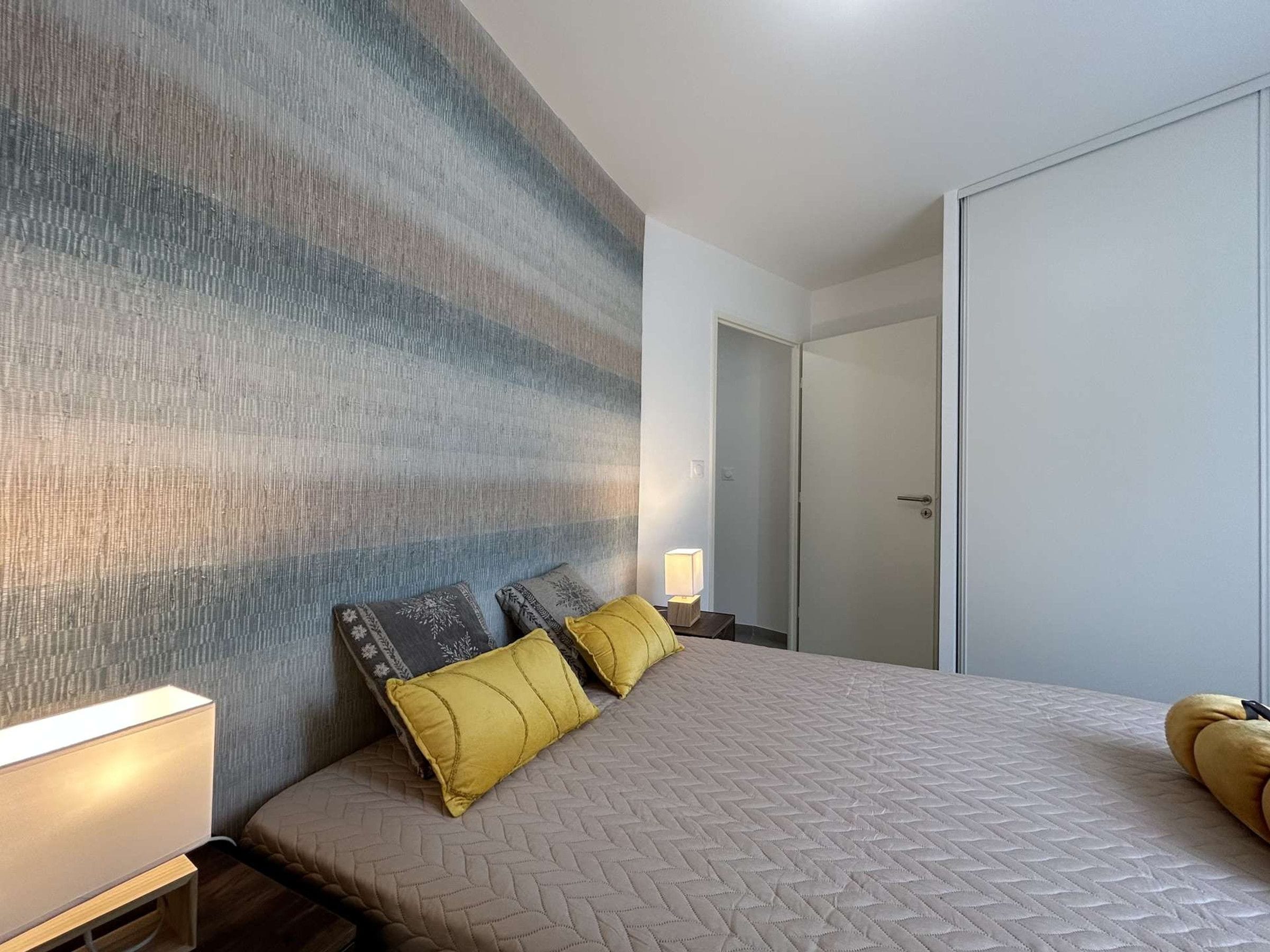 Ein Hotelzimmer mit einem großen Bett, einem Nachttisch mit Lampe und einem Kleiderschrank.