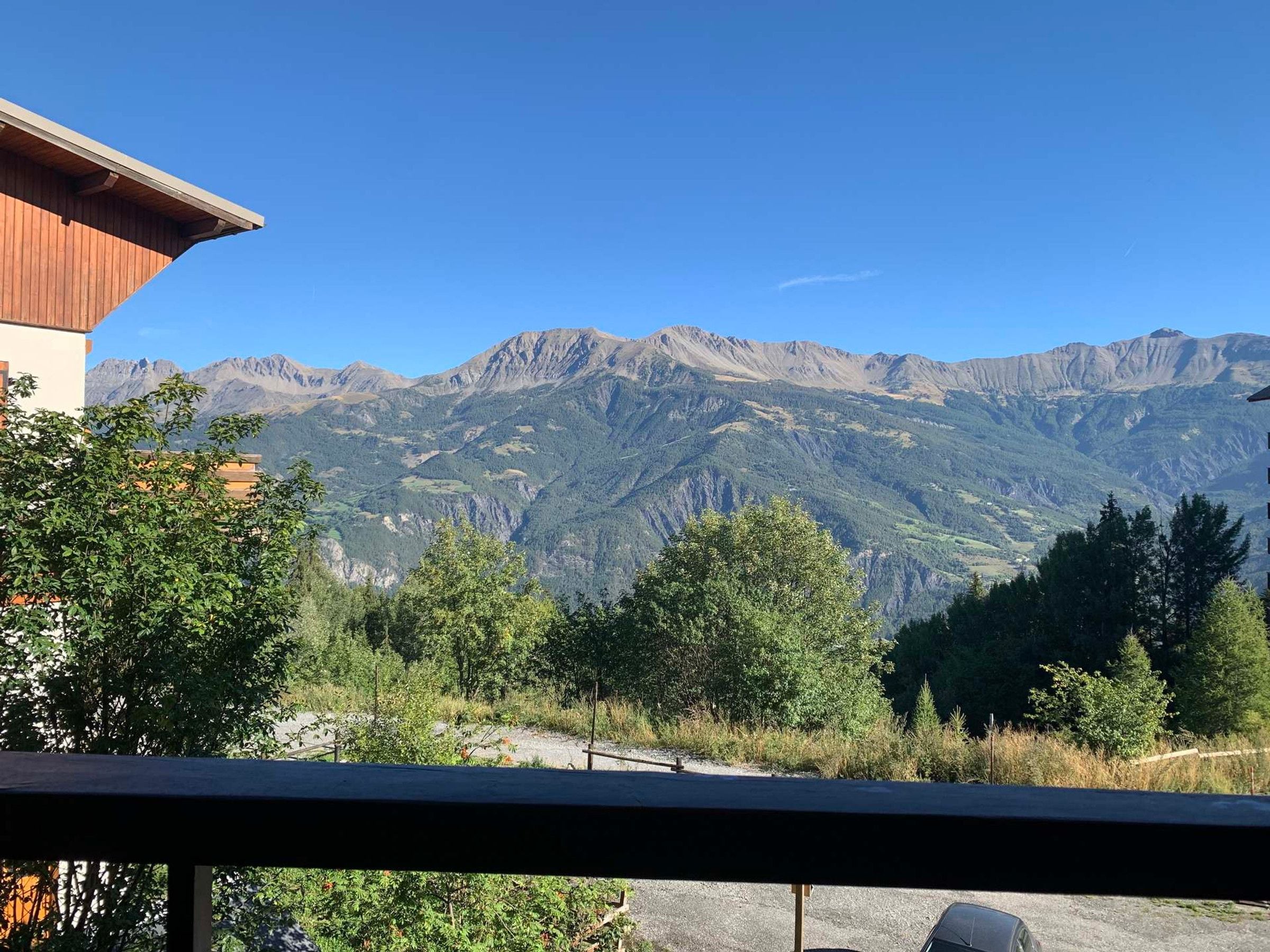 A mountain view from a balcony with a building in the foreground.