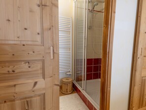 A wooden door leading into a bathroom with a shower, a white radiator, and a small wooden stool. - Central apartment with large terrace (Les Deux Alpes)