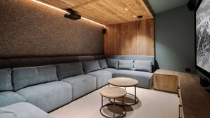 Un salon moderne avec un canapé d’angle, deux tables rondes et un meuble en bois.