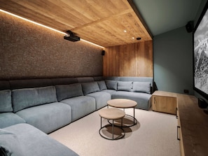 Uma sala de estar moderna com sofá seccional, duas mesas redondas e um armário de madeira.