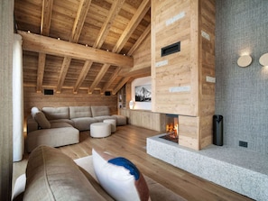 A cozy log cabin interior with a fireplace, wooden beams, and a sectional sofa. - Chalet at the slopes - 12 guests (Méribel Village)