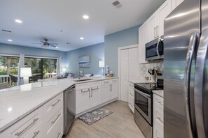 A modern kitchen with white cabinetry, stainless steel appliances, and a large window overlooking greenery. - 22 Ocean Breeze: 3 Bedrooms, Hosts 6, Walk to Beach! (Hilton Head Island)