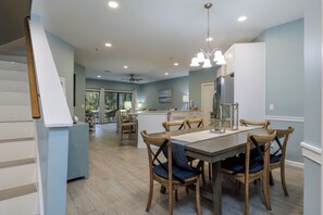 A modern kitchen with a central island, wooden chairs, and a dining table. - 22 Ocean Breeze: 3 Bedrooms, Hosts 6, Walk to Beach! (Hilton Head Island)