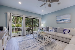 A living room with a sofa, a coffee table, a TV, and a painting on the wall. - 22 Ocean Breeze: 3 Bedrooms, Hosts 6, Walk to Beach! (Hilton Head Island)