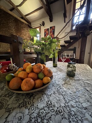 Et bord med en skål appelsiner, en vase med blomster og et glas syltetøj.
