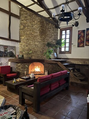A cozy living room with a stone fireplace, red sofas, and a wooden ceiling.