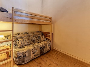 Ein Etagenbett mit Holzrahmen und einer Matratze, die mit einer gemusterten Decke bezogen ist.
