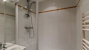 Une salle de bain avec une douche à parois de verre, un lavabo blanc et un miroir.