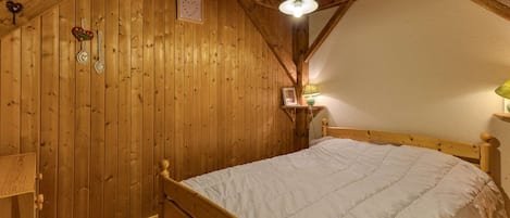 Une pièce en bois avec un lit, une table de chevet et une étagère fixée au mur.