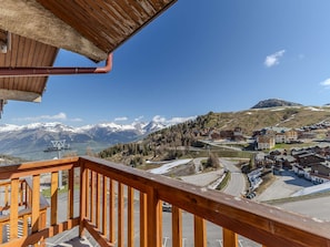 A wooden balcony overlooking a mountainous landscape with a ski resort in the background. - Renovated alpine apartment, mountain view - 10 guests (Plagne Villages)