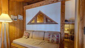L’intérieur d’un chalet en bois, avec un canapé, une lampe et un meuble en bois.