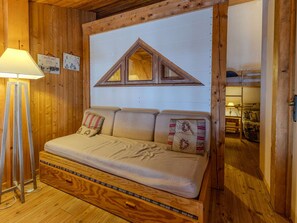 Interior de uma cabana de madeira com sofá, abajur e armário de madeira.