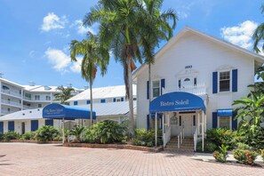 A white building with a blue awning labeled 'Bistro Soleil' and a number '1883' above the entrance. - Olde Marco Inn Unit 208 | Walk To Food, Shops & More (Marco Island)