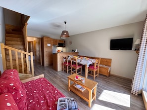 A compact living space with a dining area, kitchenette, and a staircase leading to an upper level.
